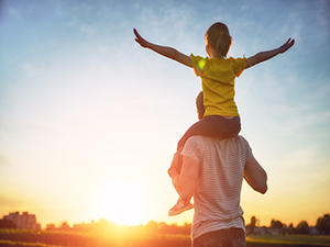 A person holding a young child on their shoulders.