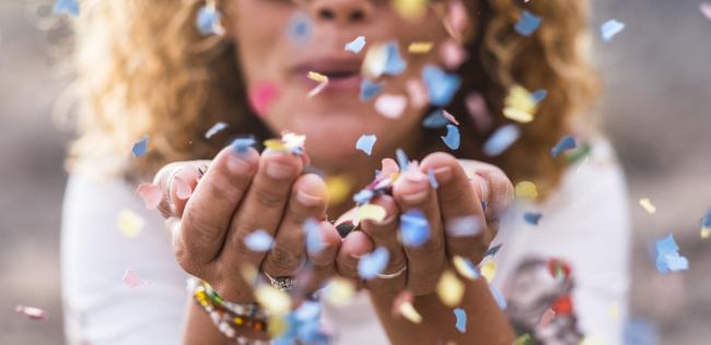 A person blowing confetti at the camera