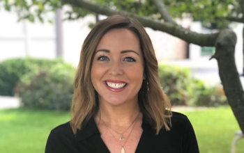 Photo of United Way of Racine County President and CEO Ali Haigh, a grinning white woman with brunette hair to her shoulders.