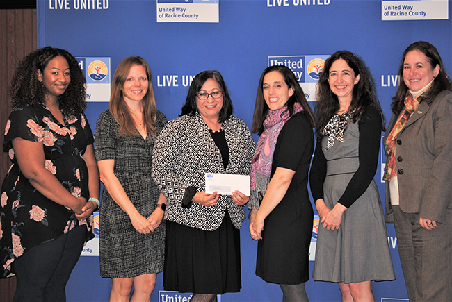 Women United's committee poses with one of their grant recipients.