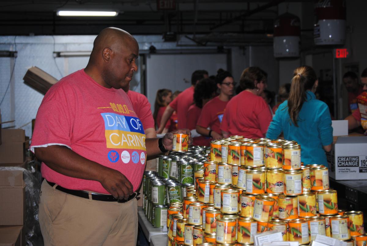 Photo of a Day of Caring volunteer stacking cans of food at the Racine County Food Bank.