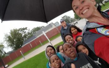 Jamie Racine grins, holding an umbrella over a group of Knapp Elementary students that she and Mike Baus are walking to school. Mike is bringing up the rear.