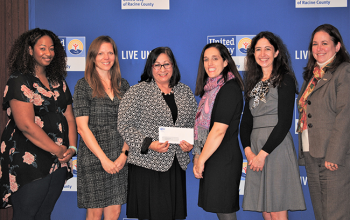Women United's committee poses with one of their grant recipients.