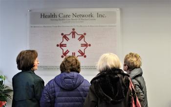 Guests of Health Care Network look up at its plaque of donors.