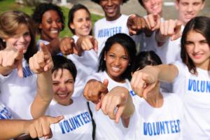 People pointing at the camera while wearing shirts that say "volunteer"